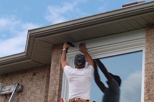 A repairman, repairing roofing and window surround